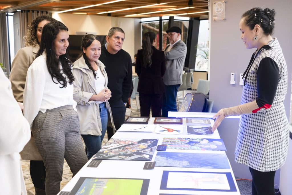 Elsa Quicazán presentando ilustraciones inspiradas en el océano, incluida la obra Atardecer en Scheveningen, durante un evento de EEMa Colombia sobre energía eólica marina.