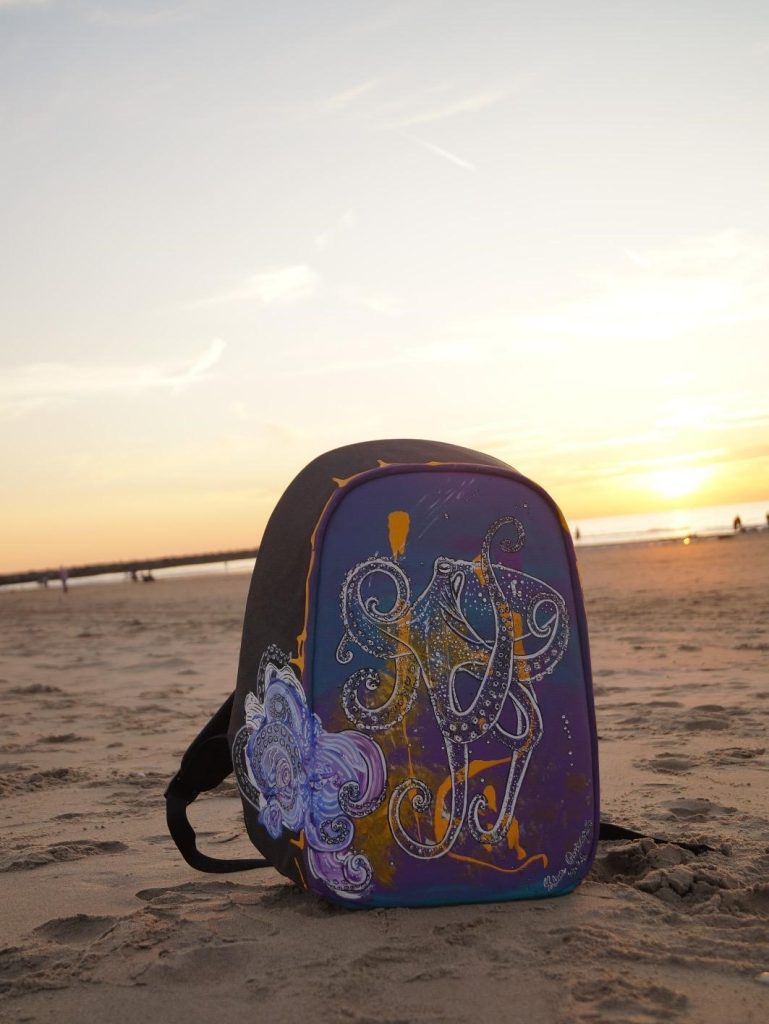 The Traveling Octopus, an acrylic painting on a suitcase photographed on Scheveningen Beach in the Netherlands.